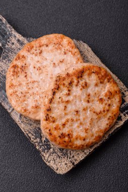 Koyu beton zeminde tuzlu, baharatlı ve otlu ızgara tavuk burgeri.