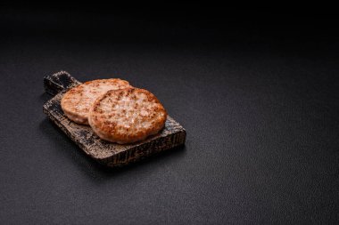 Koyu beton zeminde tuzlu, baharatlı ve otlu ızgara tavuk burgeri.