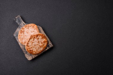 Koyu beton zeminde tuzlu, baharatlı ve otlu ızgara tavuk burgeri.