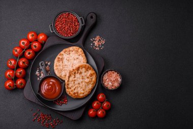 Koyu beton zeminde tuzlu, baharatlı ve otlu ızgara tavuk burgeri.