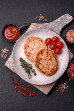 Koyu beton zeminde tuzlu, baharatlı ve otlu ızgara tavuk burgeri.