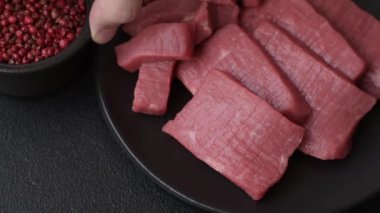 Evde yemek pişirmek için tuz ve baharatla dilimlenmiş lezzetli çiğ et.