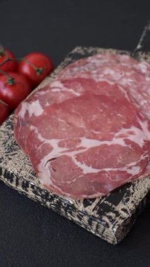 Antipasto jamon, prosciutto, sosis, domates, tuz ve baharatla dilimlenmiş koyu beton arka plan.