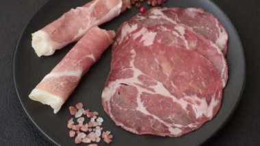 Antipasto jamon, prosciutto, sosis, domates, tuz ve baharatla dilimlenmiş koyu beton arka plan.