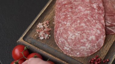 Antipasto jamon, prosciutto, sosis, domates, tuz ve baharatla dilimlenmiş koyu beton arka plan.