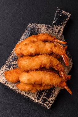 Sıcak gevrek karides, tuzlu ve baharatlı ve beyaz soslu, koyu beton arka planda.