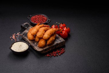 Sıcak gevrek karides, tuzlu ve baharatlı ve beyaz soslu, koyu beton arka planda.