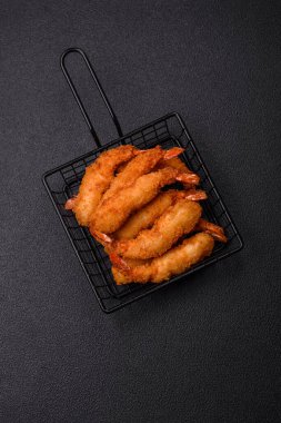 Sıcak gevrek karides, tuzlu ve baharatlı ve beyaz soslu, koyu beton arka planda.