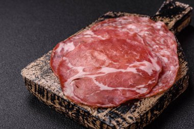 Antipasto jamon, prosciutto, sosis, domates, tuz ve baharatla dilimlenmiş koyu beton arka plan.