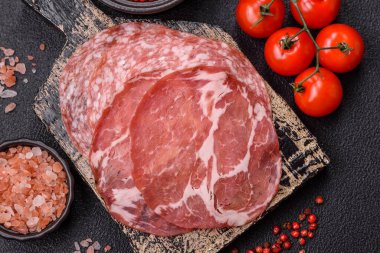 Antipasto jamon, prosciutto, sosis, domates, tuz ve baharatla dilimlenmiş koyu beton arka plan.