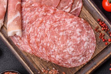 Antipasto jamon, prosciutto, sosis, domates, tuz ve baharatla dilimlenmiş koyu beton arka plan.
