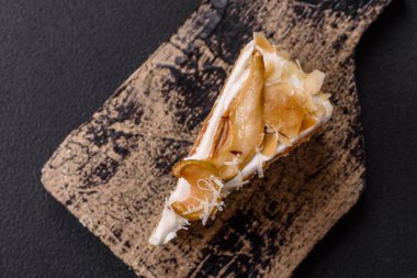 Krema, armut ve dorblu peynirli, koyu beton arkaplanda katmanlı tatlı pasta.