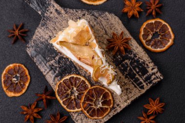 Krema, armut ve dorblu peynirli, koyu beton arkaplanda katmanlı tatlı pasta.