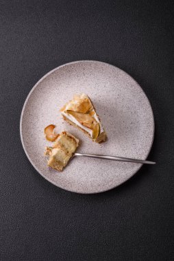 Krema, armut ve dorblu peynirli, koyu beton arkaplanda katmanlı tatlı pasta.