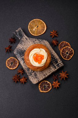 Beyaz krema ve turunçgille kaplı tatlı Danimarka çöreği. Koyu beton bir arka planda krema doluyor.