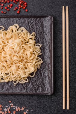 Pirinç eriştesi, soya soslu Asya yemeği ve koyu beton arka planda baharatlar.