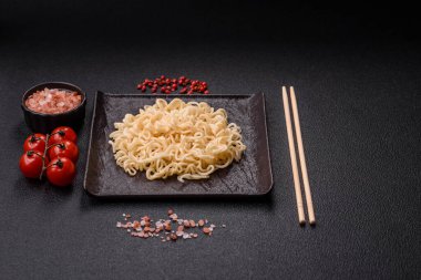 Pirinç eriştesi, soya soslu Asya yemeği ve koyu beton arka planda baharatlar.