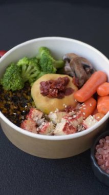 Koyu beton bir zeminde seramik tabakta sebzeli, taneli, tohumlu ve baharatlı haşlanmış biftek.