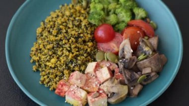 Soya peyniri, buğulanmış sebzeler, tahıllar, tohumlar ve baharatlar ile koyu beton bir arka planda.