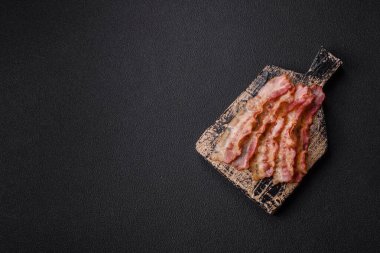 Pastırma dilimlenmiş, tuzlu ve baharatlı, koyu beton bir arka planda.