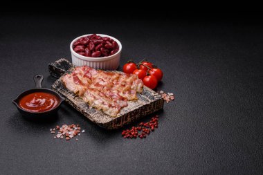 Pastırma dilimlenmiş, tuzlu ve baharatlı, koyu beton bir arka planda.