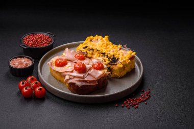 Brioche, et, erimiş peynir, jambon, domates, tuz, baharat ve otlu sandviç.