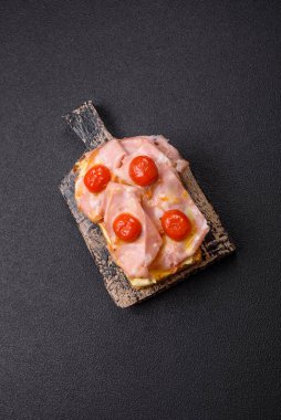 Brioche, et, erimiş peynir, jambon, domates, tuz, baharat ve otlu sandviç.