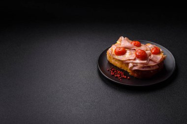 Brioche, et, erimiş peynir, jambon, domates, tuz, baharat ve otlu sandviç.