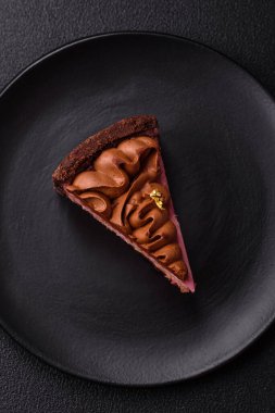 Çilek aromalı mascarpone peynirli bir parça tatlı cheesecake. Koyu beton arka planda çikolata ile kaplanmış.