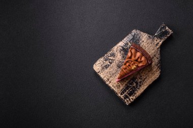 Çilek aromalı mascarpone peynirli bir parça tatlı cheesecake. Koyu beton arka planda çikolata ile kaplanmış.