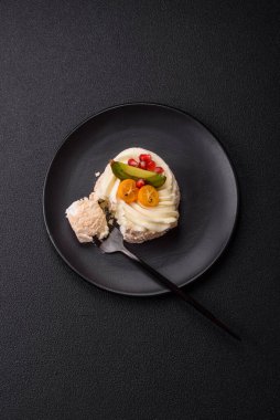 Turunçgil, kivi ve nar tohumlu, koyu beton arkaplanda bir parça tatlı krema.