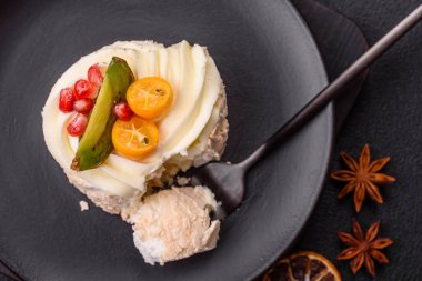 Turunçgil, kivi ve nar tohumlu, koyu beton arkaplanda bir parça tatlı krema.