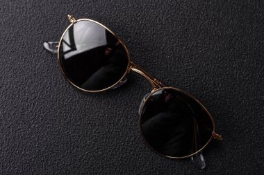Koyu beton arka planda yuvarlak lensli modaya uygun güneş gözlükleri.