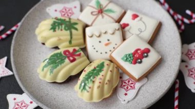 Tatlı Madeleine tatlıları Noel renklerinde çikolatayla kaplıdır. Koyu beton arka planda çeşitli malzemeler vardır.