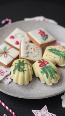 Tatlı Madeleine tatlıları Noel renklerinde çikolatayla kaplıdır. Koyu beton arka planda çeşitli malzemeler vardır.