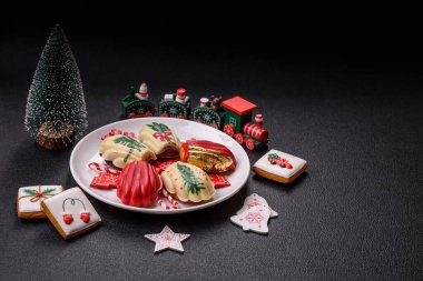 Tatlı Madeleine tatlıları Noel renklerinde çikolatayla kaplıdır. Koyu beton arka planda çeşitli malzemeler vardır.