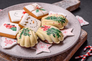 Tatlı Madeleine tatlıları Noel renklerinde çikolatayla kaplıdır. Koyu beton arka planda çeşitli malzemeler vardır.