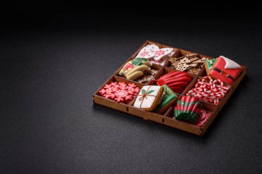 Lezzetli zencefilli çörek, madeleine bisküvileri ve koyu beton arka planda diğer Noel süsleri.