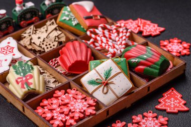 Lezzetli zencefilli çörek, madeleine bisküvileri ve koyu beton arka planda diğer Noel süsleri.