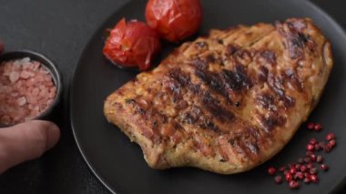 Izgarada pişirilmiş leziz domuz eti. Koyu beton arka planda tuz, baharat ve otlarla birlikte.