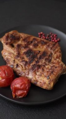 Izgarada pişirilmiş leziz domuz eti. Koyu beton arka planda tuz, baharat ve otlarla birlikte.