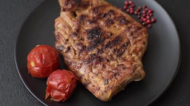 Izgarada pişirilmiş leziz domuz eti. Koyu beton arka planda tuz, baharat ve otlarla birlikte.