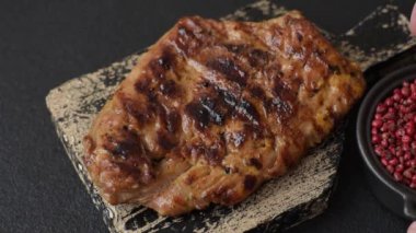 Izgarada pişirilmiş leziz domuz eti. Koyu beton arka planda tuz, baharat ve otlarla birlikte.