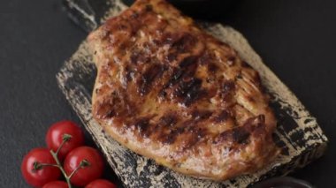 Izgarada pişirilmiş leziz domuz eti. Koyu beton arka planda tuz, baharat ve otlarla birlikte.