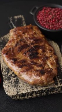 Izgarada pişirilmiş leziz domuz eti. Koyu beton arka planda tuz, baharat ve otlarla birlikte.