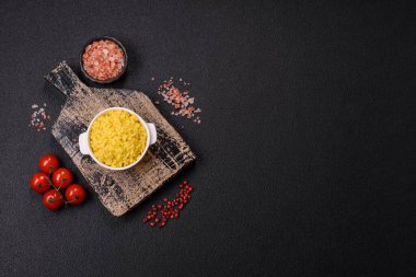 İtalyan arborio risotto pilavı. Tuz, baharat ve otlarla birlikte koyu beton bir arka planda.