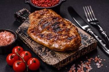 Izgarada pişirilmiş leziz domuz eti. Koyu beton arka planda tuz, baharat ve otlarla birlikte.