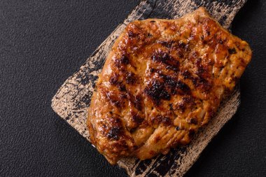 Izgarada pişirilmiş leziz domuz eti. Koyu beton arka planda tuz, baharat ve otlarla birlikte.