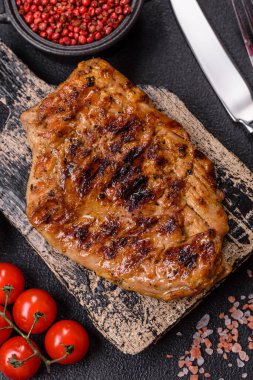 Izgarada pişirilmiş leziz domuz eti. Koyu beton arka planda tuz, baharat ve otlarla birlikte.