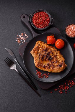 Izgarada pişirilmiş leziz domuz eti. Koyu beton arka planda tuz, baharat ve otlarla birlikte.